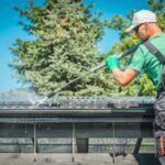 Roof and Gutters Power Cleaning Using Pressure Washer. Caucasian Worker.