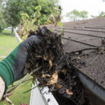 Worker cleaning gutters for a customer.