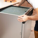 Service worker taking out dishwasher to repair a leak